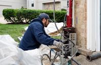 Crew installing push pier on corner of home
