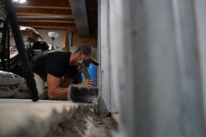 Crew installing full basement waterproofing and wall repair