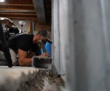 Crew installing full basement waterproofing and wall repair