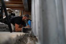 Crew installing full basement waterproofing and wall repair