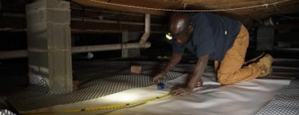 Crew installing vapor barrier in crawl space