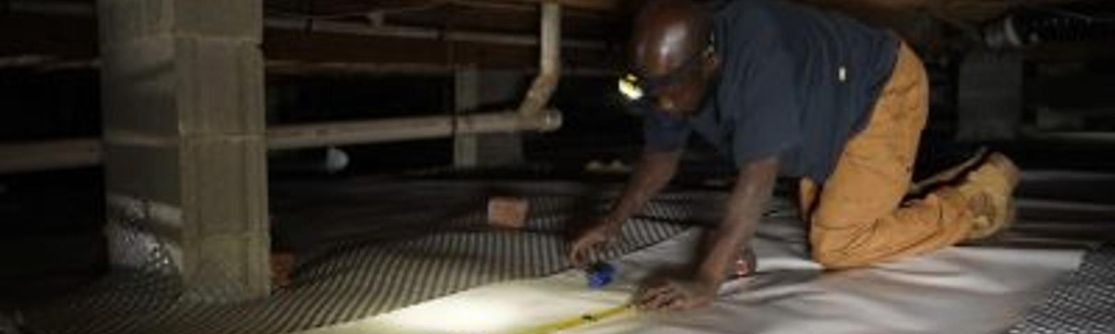 Crew installing vapor barrier in crawl space
