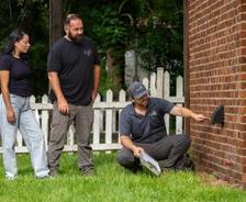 Mount Valley Foundation Services inspector and two homeowners inspecting a brick house