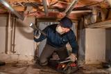 Mount Valley Foundation Services inspector assessing crawl space with a flashlight
