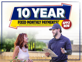 A woman talks to a smiling worker holding a clipboard; sign reads "10 Year Fixed Monthly Payments. Apply Now.”