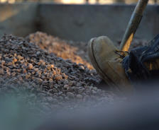 Boot pushing shovel into rocks