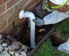 THBS production crew installing exterior pipe for basement sump pump.