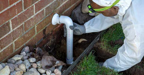 THBS production crew installing exterior pipe for basement sump pump.