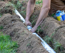 Hands are installing pipe in the exterior tunnel.