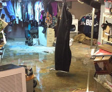 A finished basement flooding with household items damaged.