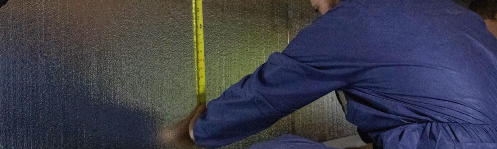 THBS is measuring crawlspace wall for a vapor barrier.