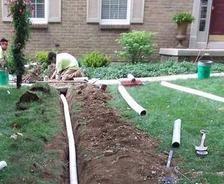THBS staff installing an exterior drainage system in the front yard.