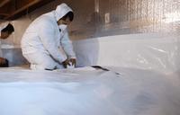 Crew installing vapor barrier for crawl space encapsulation