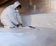 Crew installing vapor barrier for crawl space encapsulation
