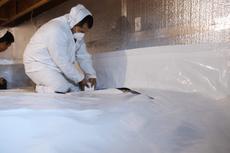 Crew installing vapor barrier for crawl space encapsulation