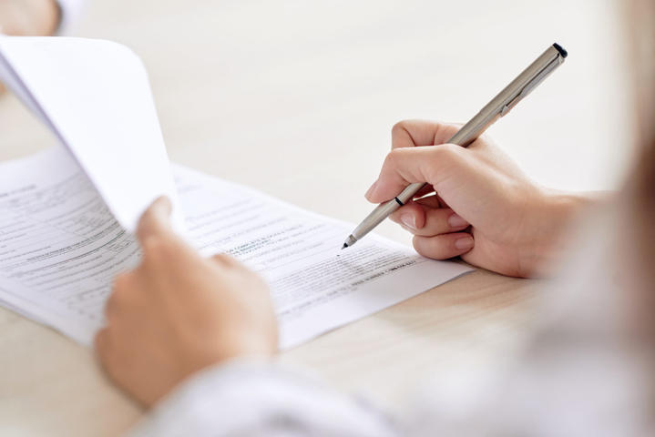 Crop shot of a person signing a contract with a pen.