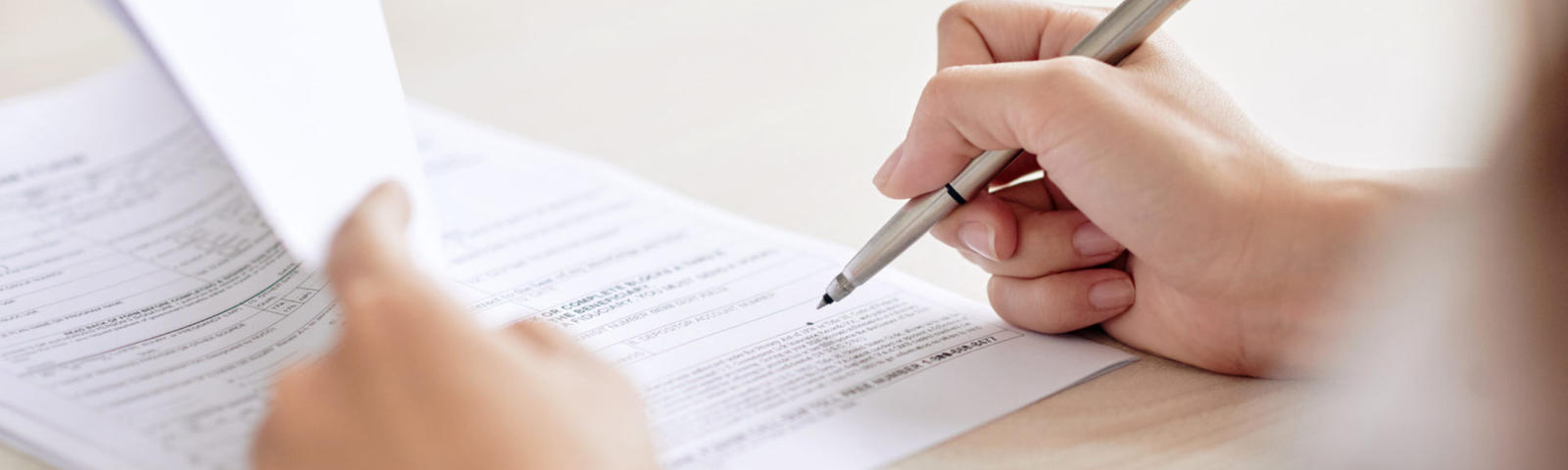 Crop shot of a person signing a contract with a pen.