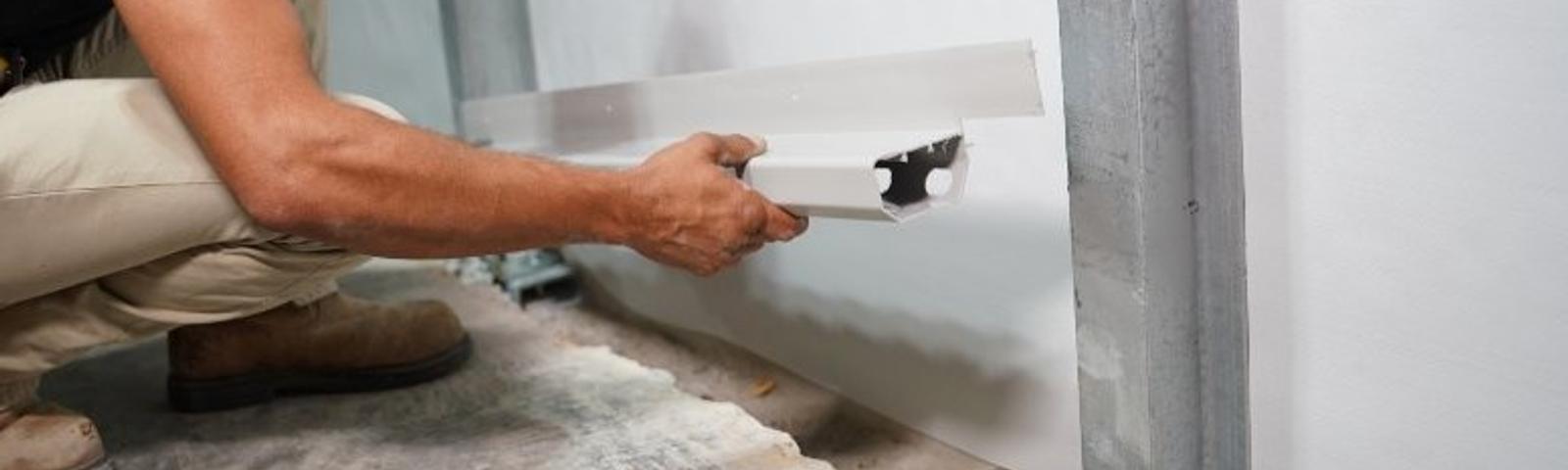 Hands holding drain in the basement floor.