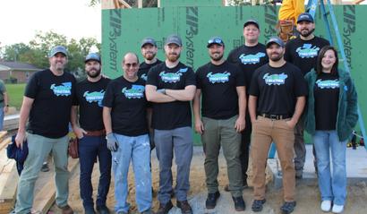 A group of people wearing matching shirts, standing together at a construction site.