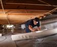 crew member rolling out a vapor barrier in a crawl space