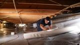 crew member rolling out a vapor barrier in a crawl space