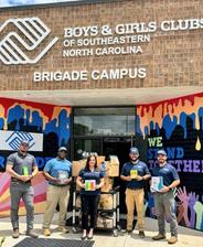 Tar Heel Basement Systems employees holding donations made to a school supply drive for Boys & Girls Clubs of Southeastern North Carolina