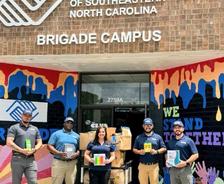 Tar Heel Basement Systems employees holding donations made to a school supply drive for Boys & Girls Clubs of Southeastern North Carolina
