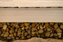 Close-up view of a gutter with light brown rocks beneath it, seamlessly integrated as part of a sump pump installation.