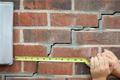 cracked exterior brick wall with tape measure