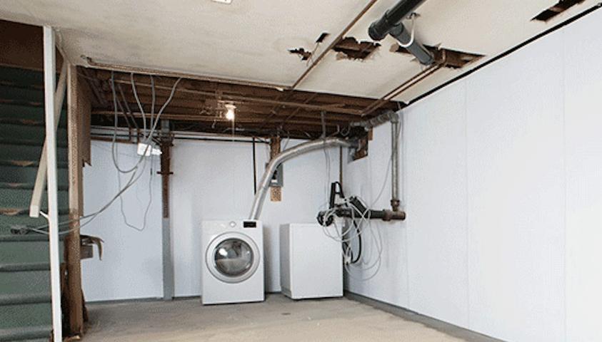 Unfinished basement with washer, dryer, exposed pipes, and wiring.