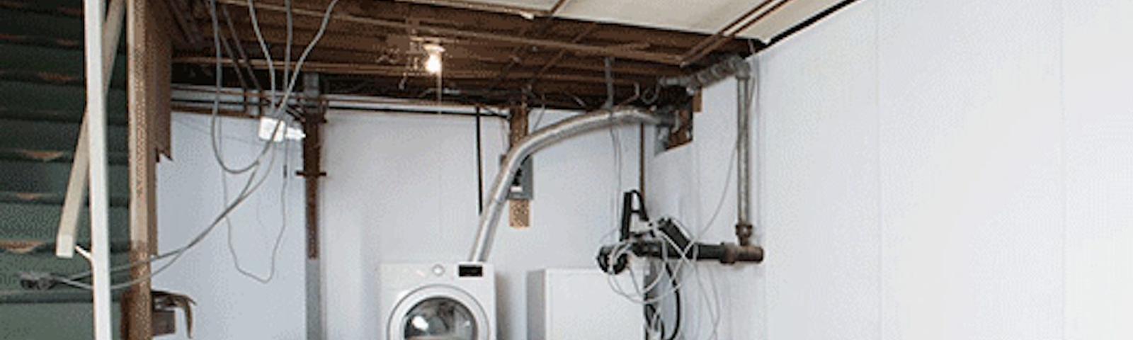Unfinished basement with washer, dryer, exposed pipes, and wiring.