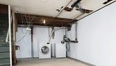 Unfinished basement with washer, dryer, exposed pipes, and wiring.