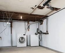 Unfinished basement with washer, dryer, exposed pipes, and wiring.