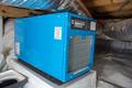 A blue crawl space dehumidifier is installed in an attic, surrounded by ductwork and insulation.