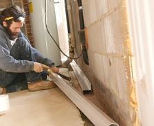 FRS crew member installing interior drainage in basement