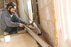 FRS crew member installing interior drainage in basement