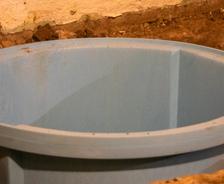 A large, round blue plastic basin, designed to withstand hydrostatic pressure problems, is partially embedded in the ground.