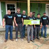 A group of seven people holding a thank you sign at a construction site.