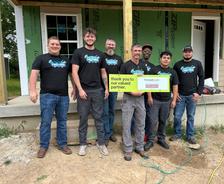 A group of seven people holding a thank you sign at a construction site.