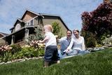 older home in the background of a family sitting on the grass
