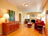 Cozy living room with wooden floors, red sofas, lamps, a fireplace, and nature artwork on the wall.