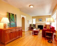 Cozy living room with wooden floors, red sofas, lamps, a fireplace, and nature artwork on the wall.