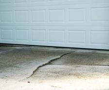 A white garage door above a concrete driveway with a visible crack.