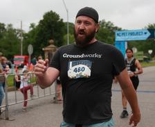 Man with a beard wearing a race bib numbered 460 walks near a finish line at an outdoor event.