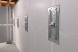 Metal wall anchor plates secured to a white basement wall, with exposed ceiling beams above.