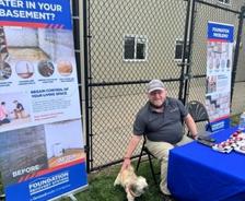 Foundation Recovery Systems employee petting a dog at a company table at the Animal Rescue League of Iowa's Yappy Hour