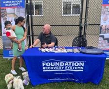 Foundation Recovery Systems employee talks to an attendee at a company table at the Animal Rescue League of Iowa's Yappy Hour