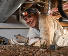 smiling crew member in a crawl space