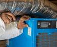 crew member installing a dehumidifier in a basement