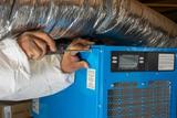 crew member installing a dehumidifier in a basement